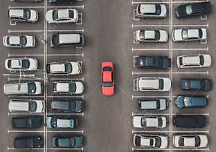 Top view of the crowded Parking lot with quadcopter or drone. Original bright automobile among the grey of mediocre cars. Parking
