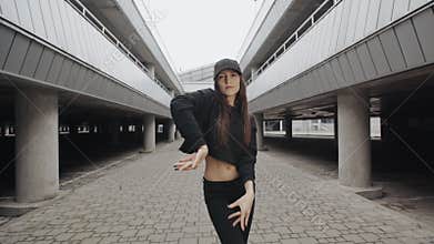 Woman dancing, performs modern vogue dance in parking, contemporary freestyle in urban environment