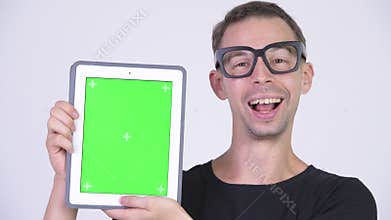 Studio shot of happy nerd man showing digital tablet