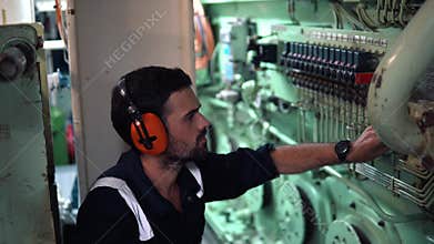 Marine engineer inspecting ship`s engine in engine control room