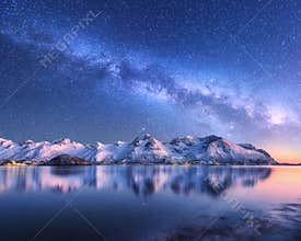 Milky Way over snow covered mountains and sea at night in winter