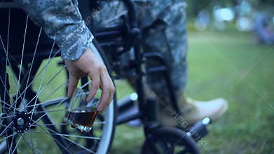 Injured soldier in wheelchair holding whisky glass posttraumatic stress disorder