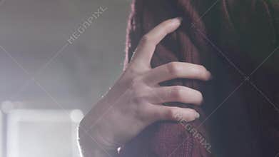 Woman`s hand with long nails grabs man`s arm wearing brown knitted pullover.