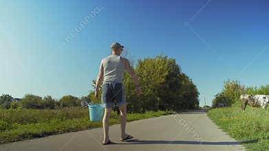 Rural Man Carries A Bucket Of Water For Watering