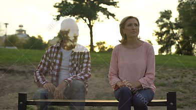 Depressed old woman sitting on bench, husband appearing beside, loss, memories