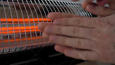 Man warming his hands near the heater. 4K