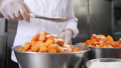 Hands pastry chef spread the sugar on the apricots fruit, prepare the jam in industrial kitchen