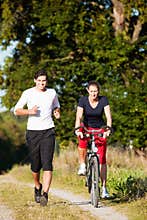 Young sport couple jogging and cycling