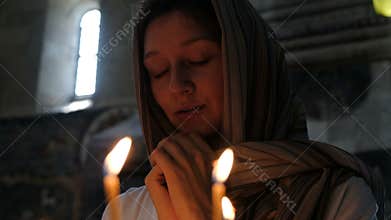 Woman in a headscarf praying in an Orthodox Catholic church