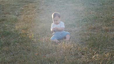 Small baby girl sitting on grass in park. Beautiful infant baby girl portrait in nature