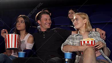 Handsome young macho man hugging two girls at the cinema