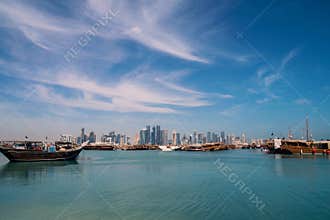 DOHA, QATAR - Feb 2018: Beautiful Doha Skyline View with Traditional Wooden Boats with Floating Qatar Flags. Corniche