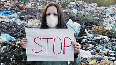 Woman activist with Stop poster on waste dump