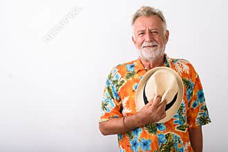 Studio shot of handsome senior bearded tourist man holding hat o