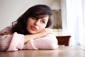 Sad woman in contemplation sitting and leaning on table