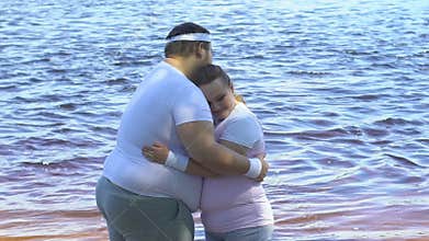 Overweight man hugging his cute plump girlfriend near river, tenderness and love