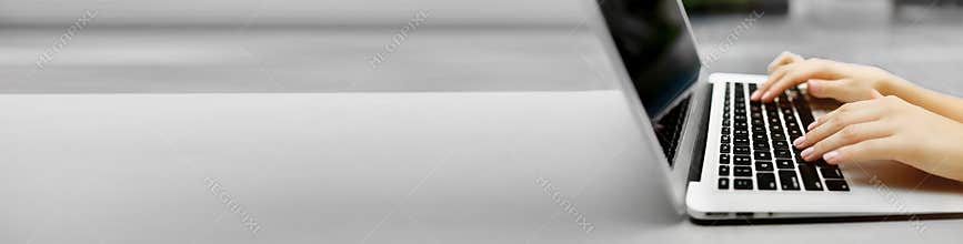 Banner of laptop and female hands with copyspace in grey color background.