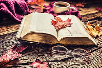 Cup of coffee old book glasses and autumn leaves.