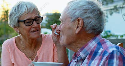 Senior woman feeding senior man in backyard 4k