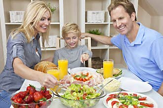 Family Eating Healthy Food & Salad At Dining Table