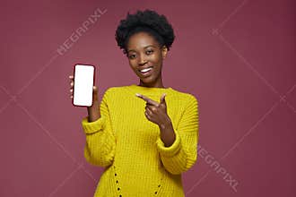 Modern young african american girl show phone with blank screen. New entertaining or dating mobile app advertising