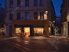 View of illuminated shop La Cure Gourmande, offering provencal products, in the center of Avignon, Provence, France.