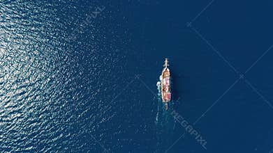 Aerial top down: cruise ship sailing on open sea with clear blue water