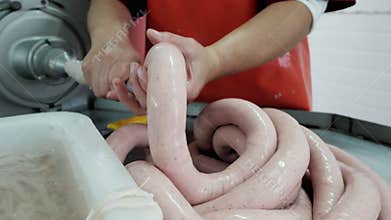 Sausage production process in a meat factory, worker shapes the sausage.