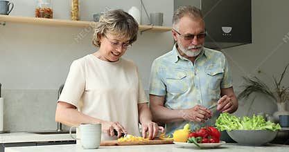 Friendly older age spouses talk while preparing breakfast at kitchen