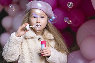 Kid birthday party concept. girl in beret playing with pink, purple balloons, outdoors. childrens emotions.