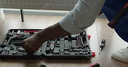 black professional plumber worker installing heating radiator in an empty room