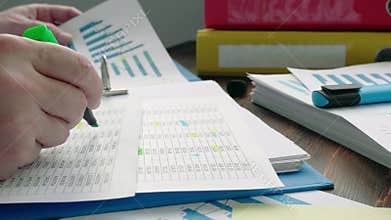 The auditor checks the financial statements. Close-up of a hand with highlighting the data.
