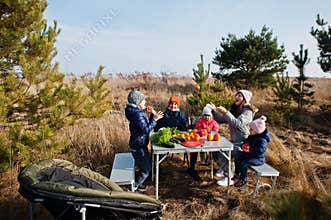 Cheerful mother with kids at a picnic. Family on vacation with fruits outdoor
