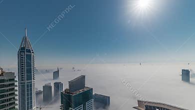 Rare early morning winter fog above the Dubai Marina skyline and skyscrapers rooftops aerial timelapse.