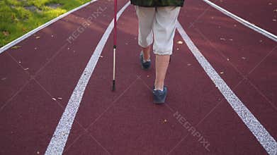 Legs of a senior woman doing Nordic walking on a sports jogging track stadium. Sport lifestyle in old age concept.