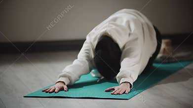 Yoga indoors - young woman in hijab doing exercises for her back and spine