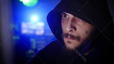 Male criminal hacker working on a computer in a dark office room. Cyber attack breaking computer security