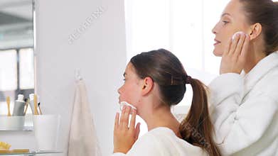 mother and daughter with cotton pads cleaning skin