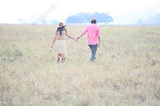 Couples of man and woman holding hand in grass field