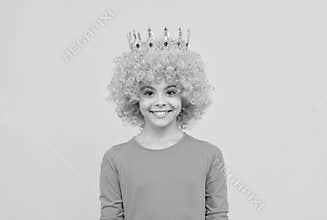 girls birthday party. happy funny kid in curly wig and crown. imagine herself a queen.