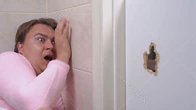 Scared man with toothbrush hides in bathroom from evildoer