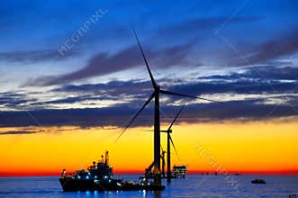 Offshore windfarm construction at sunset