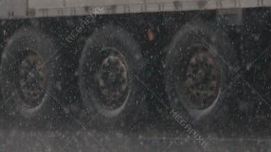 Snowfall sleet falls on highway against powerful wheels
