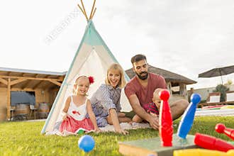 Parents playing bowling with children while camping in the backyard