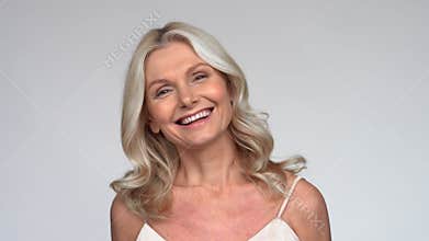 Happy 50s middle aged mature woman looking at camera and laughing.