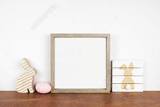 Mock up square wood frame with shabby chic Easter decor on a wood shelf against a white wall