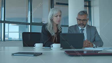 Serious business colleagues watching content on laptop