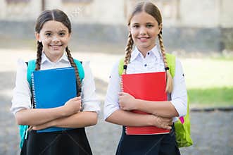 Happy kids in school uniforms hold study books outdoors, development