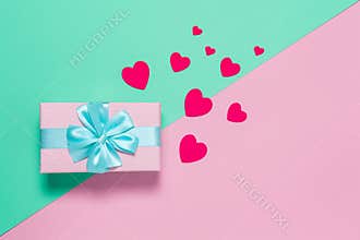 Pink gift box with blue bow on pastel two-color background pink and mint, copy space, flat lay. March 8, February 14, birthday, St