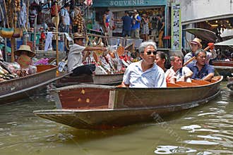 Tourists relaxing on wooden boat at floating market with vendors selling souvenirs around Bangkok area  Thailand